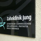 Selbstklebendes Arztschild aus schwarzem Acrylglas mit Folienschrift und edlem Wasserzeichen-Effekt in Frankfurt.