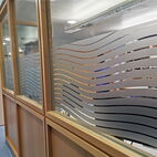 Satinierte Sichtschutzfolie mit modernem Wellen-Design für Fenster und Glastüren einer Klinik in Berlin.