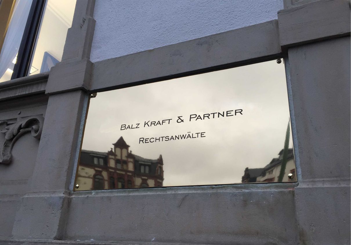 Spiegelglänzendes, graviertes Messingschild für den Außenbereich mit tiefschwarz eingefärbter Gravur und Dekokappen in Augsburg.